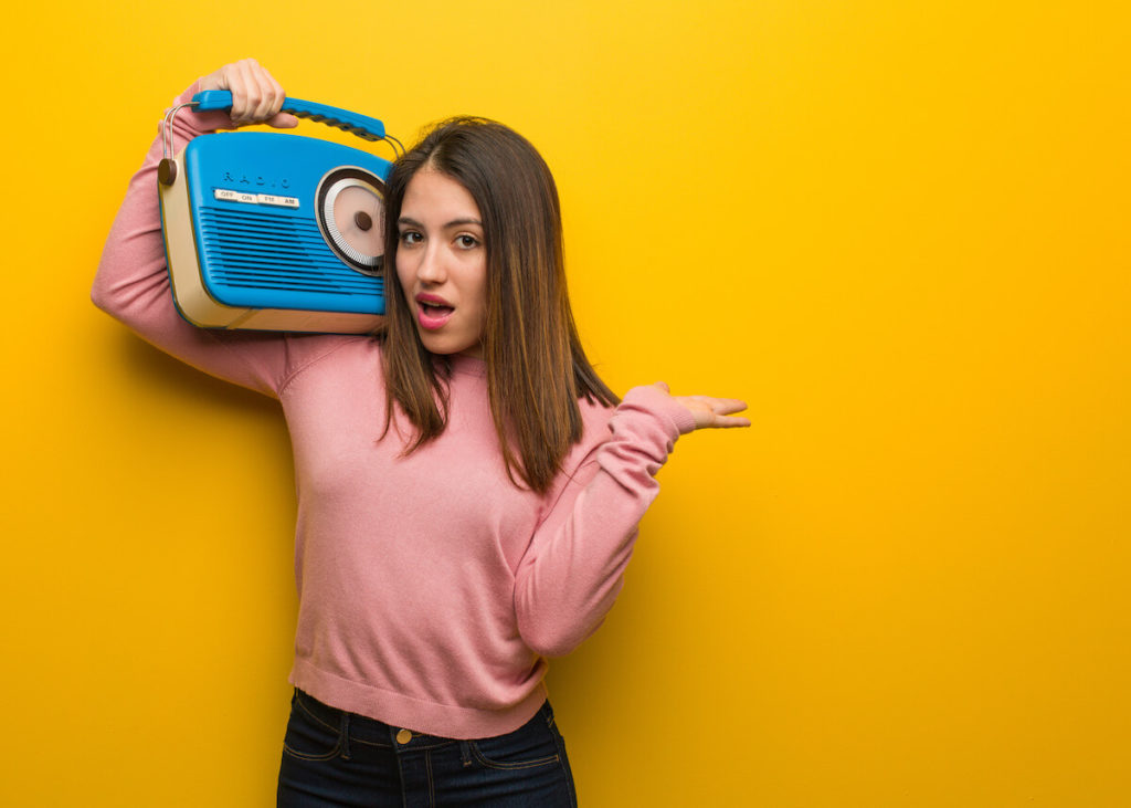 Woman holding a boombox listening to radio advertising