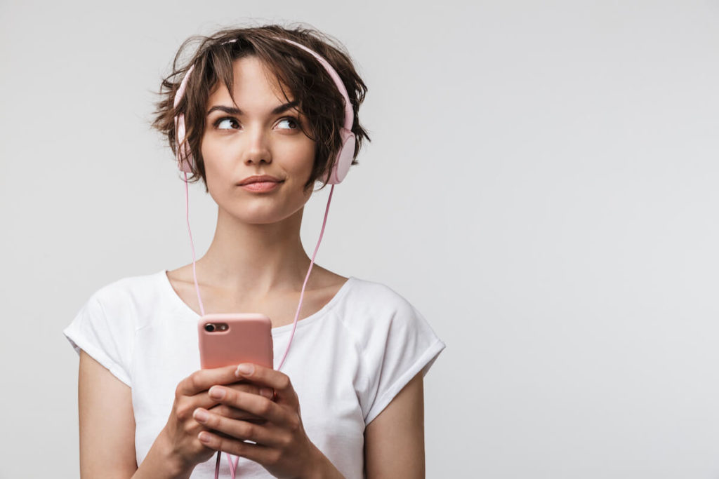 Woman wearing headphones listening to Youtube audio ads from her mobile