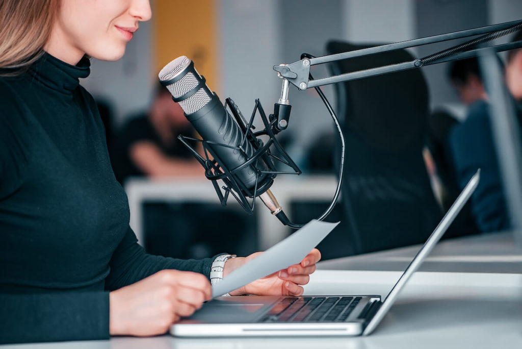 Podcasts sponsorship pricing: woman reading a script while recording